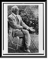 Frank Lloyd Wright, full-length portrait, seated in chair outdoors, facing right, left hand extended palm up, Vintage Print