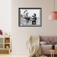 Mrs. Marion John Miles holding baby, while Oneida Chief William H. Rockwell demonstrates how stripes on squash determine the celebration of the gathering of the harvest, Oneida Lake, New York Cla