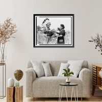 Mrs. Marion John Miles holding baby, while Oneida Chief William H. Rockwell demonstrates how stripes on squash determine the celebration of the gathering of the harvest, Oneida Lake, New York Cla