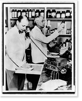 A pharmacist demonstrates the use of a telephone disc prescription recorder as G.W. Wallace fills a prescription Classic, Antique Print