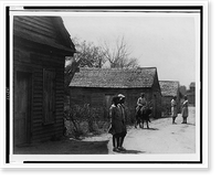 Two African American women and three children, one of them on a cow, on an unpaved road, in front of buildings, Vintage Poster