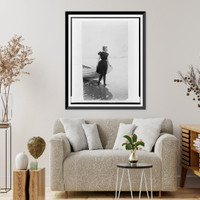 Historic Framed Print, [Frances Benjamin Johnston, full-length portrait, standing at edge of ocean, in bathing suit, with left hand on boat, facing right],  17-7/8" x 21-7/8"