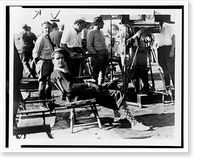 Howard Hughes, full-length portrait, seated, facing front, film crew in background, during filming of Sky devils"" Classic, Antique Print