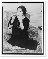 Romola Najinsky, full-length portrait, seated on sofa, facing left, lighting cigarette, Antique Poster