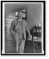John Ford, three-quarter length portrait, standing, facing slightly right, with his left hand on rolltop desk, Antique Poster