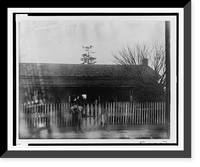 African American man standing at tall picket fence in front of house, Vintage Poster