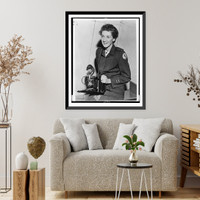 Historic Framed Print, [Toni Frissell, half-length portrait, seated, facing slightly left, in Red Cross uniform, holding camera],  17-7/8" x 21-7/8"