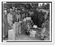 Private Sam Oka hands over to Private Henry Oshiro his share of the generous gifts of candies and cigarettes sent to members of the Japanese-American Combat Team by a Hawaiian pineapple company Her