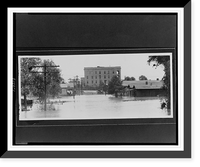 Houses, trees, and utility poles partially submerged by flood waters, in the distance, buildings on higher ground.Ewing, Inc., Baton Rouge, Vintage Poster