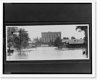 Houses, trees, and utility poles partially submerged by flood waters, in the distance, buildings on higher ground.Ewing, Inc., Baton Rouge, Vintage Poster