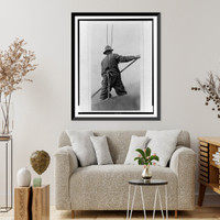 Man, secured by ropes, with back to camera, holding pole, body of water in background Classic, Antique Print