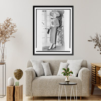 Historic Framed Print, [Christine Jorgensen, full-length portrait, standing, facing slightly left, wearing large straw hat and orchid corsage as she leaves the Adelphi Theater in New York City],  17-7/8" x 21-7/8"