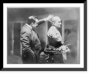 Enrico Caruso, 1873-1921, three-quarter length portrait, standing, right profile, examining a bust sculpture of himself, Vintage Print