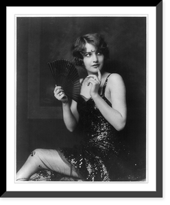 Barbara Stanwyck, three-quarter length portrait, seated, turned to the left, holding fan, Historic Reproduction