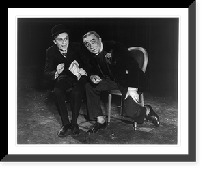 2 actors seated on chairs on stage, one is leaning forward with arm on leg and pointing, Historic Print