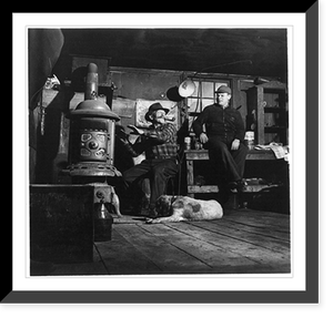 Andrew Scavnicky and his buddy, John Mikula, coal miners, loafing in Andrew's workshop, with dog, Hazelton, Pa.: Interior with Andrew warming his hands at stove, Historic Print