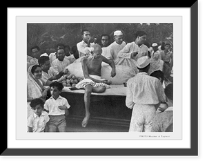 Historic Framed Print, [Mahatma Gandhi, full-length portrait, seated, with group of people around him].photo Khopkar & Engineer.,  17-7/8" x 21-7/8"