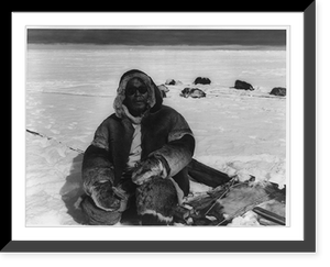 An elderly Eskimo man, wearing clothes made from caribou skin, in front of dog team watching the Coast Guard icebreaker Eastwind depart the Cape Christian area, Vintage Poster
