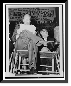 Adlai E. Stevenson, full-length portrait, seated, facing front, studying his speech notes, at a campaign rally in the Harlem section of New York City, Vintage Poster