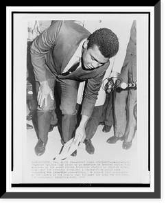 Historic Framed Print, [Muhammad Ali, formerly Cassius Clay, stooping to pick up envelope at entrance to the Armed Forces examining and entrance station in Houston, Texas],  17-7/8" x 21-7/8"