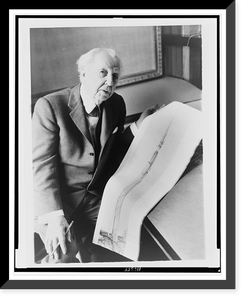 Frank Lloyd Wright, three-quarter length portrait, seated, facing front, holding sketch of a 528 story office building he designed, Antique Poster