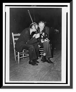 Fiddling Bill Hensley and his rival for Old Time Fiddlers' Championship, Asa Helton, both seated and talking, holding their fiddles, at the Mountain Music Festival, Asheville, North Carolina Time