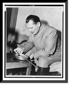 Hermann G&ouml;ring, three-quarter length portrait, seated on bed(?), facing left, eating from pan.U.S. Army Signal Corps, Vintage Poster