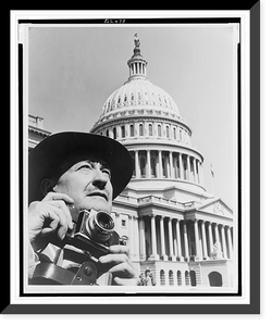 Photograph shows an unidentified photographer holding his camera, and the dome of the U.S. Capitol, silhouetted against the sky, Vintage Print