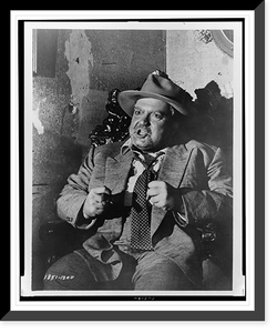 Orson Welles, three-quarter length portrait, seated, facing front, with his fists clenched before him in a scene from the movie Touch of evil"", Vintage Print