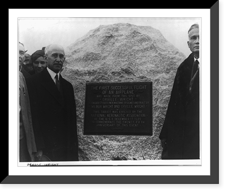 Orville Wright standing with group at memorial to first successful air flight, three-quarter length protrait, facing right, Historic Print