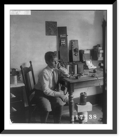Historic Framed Print, [Boy holding receiver to ear, listening to a radio],  17-7/8" x 21-7/8"