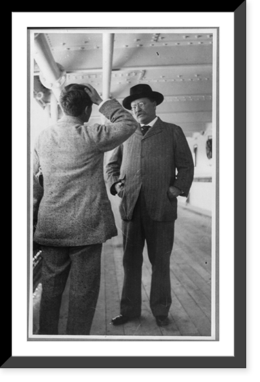 Theodore Roosevelt, full length, standing with hands in coat pockets, facing left, talking with G. Gardner on the KAISERIN AUGUSTE VICTORIA, Vintage Poster