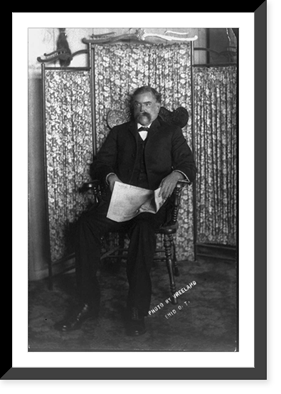 David E. George, full-length portrait, seated, facing left, holding newspaper Classic, Vintage Poster