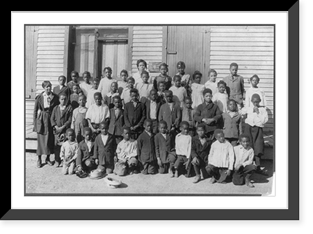 Historic Framed Print, [Group portrait of African American students and one adult, possibly teacher, standing outside a school house],  17-7/8" x 21-7/8"
