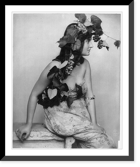 Young woman posed, seated, three-quarters length, facing right; with grapes, vines and leaves draped over head, Vintage Wall Art