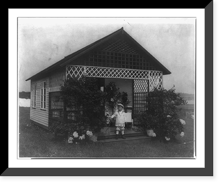 Master Vinson Walsh McLean on steps of latticed porch of his play cottage, holding tennis racket, Vintage Print