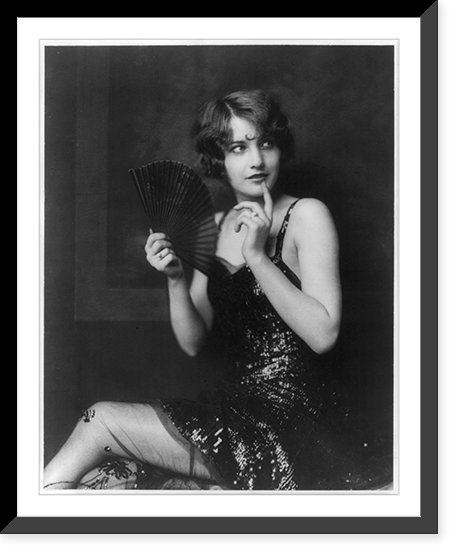 Barbara Stanwyck, three-quarter length portrait, seated, turned to the left, holding fan, Historic Reproduction