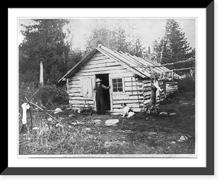 Man with shotgun at doorway of cabin and a deer hanging from pole at camp, Eighth Lake, Fulton Chain, Adirondack Mountains, N.Y, Historic Print