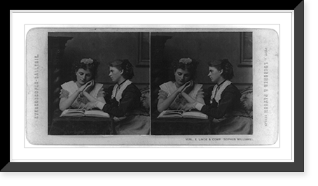 Historic Framed Print, [Woman looking at book as another woman points to something in the book],  17-7/8" x 21-7/8"