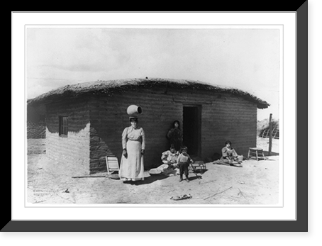 Five Pima Indians posed outside adobe house. one woman is standing with a piece of pottery on her head Classic, Vintage Print