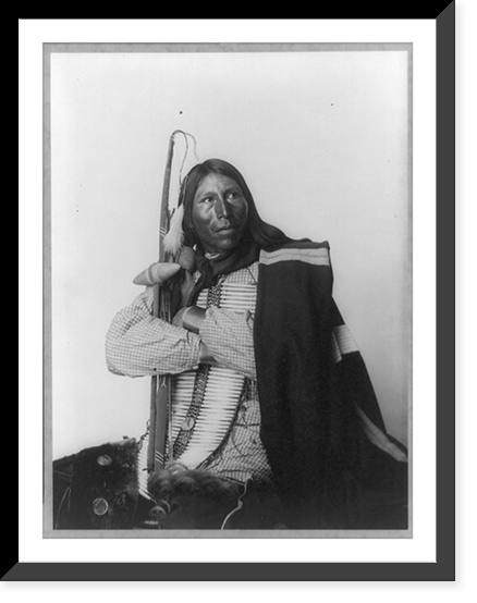 Distributor, Native American man, three-quarter length portrait, seated, facing right; arms folded, holding bow, arrow, and tomahawk; dressed in bone breast plate, Antique Wall Art