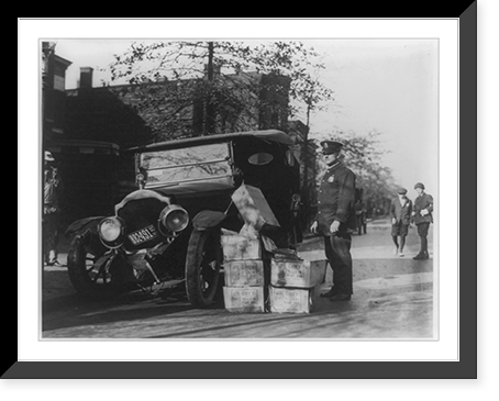 Policeman standing alongside wrecked car and cases of moonshine, Historic Reproduction