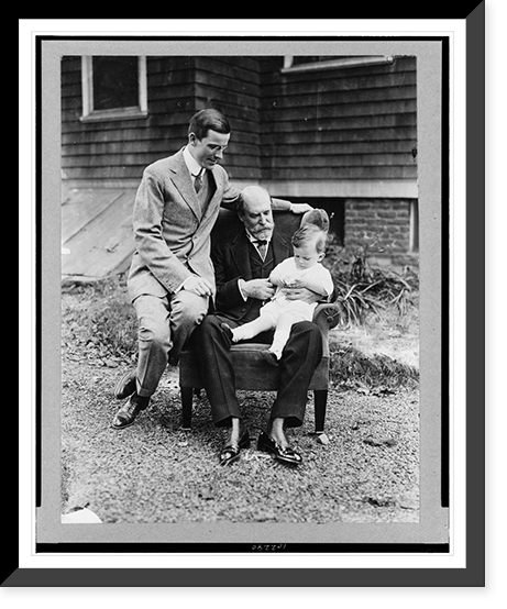 Charles Evans Hughes, seated, full-length, holding his grandson, with Charles Evans Hughes, Jr. seated on arm of the same chair, Vintage Poster