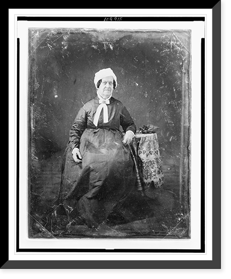 Unidentified woman, about 60 years of age, full-length portrait, facing front, seated beside small table with tablecloth and handbag, wearing white cap, Vintage Poster