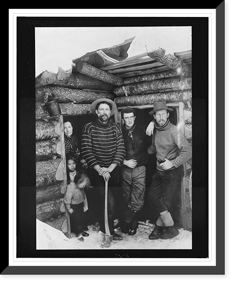 Three men, one of them holding an axe, a woman, and four children standing at two doorways of a log cabin Classic, Historic Print