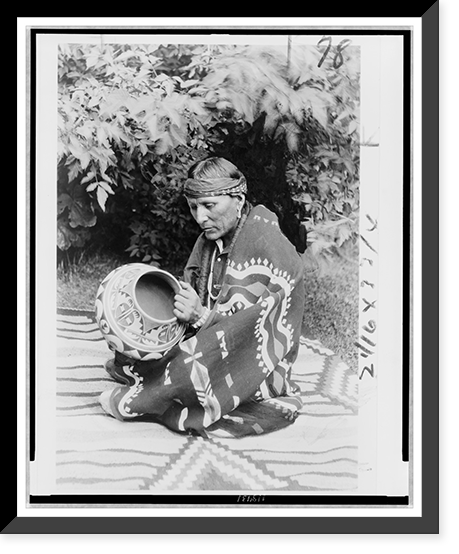San Ildefonso Pueblo man Julian Martinez, seated on et, facing left holding pottery, Vintage Poster