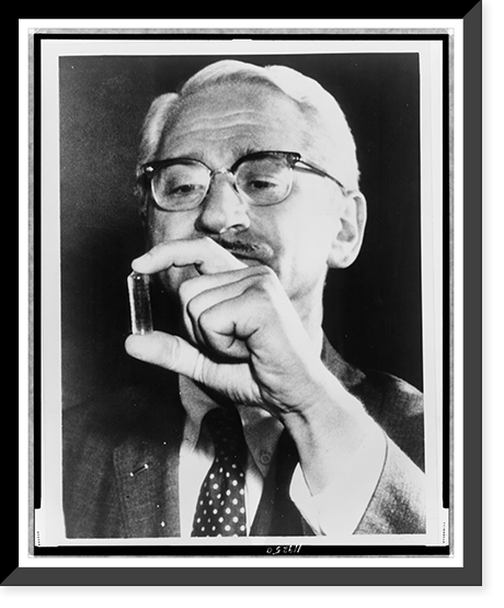 Dr. Albert Sabin, head-and-shoulders portrait, facing slightly left, examining a vial that held a live-virus vaccine for polio, Historic Print