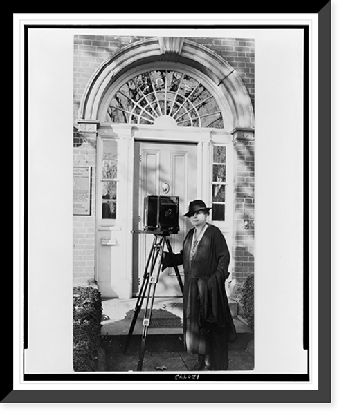 Historic Framed Print, [Frances Benjamin Johnston, full-length portrait, standing in front of door, with camera, facing slightly left],  17-7/8" x 21-7/8"