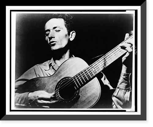 Historic Framed Print, [Woody Guthrie, half-length portrait, facing left, singing and playing guitar],  17-7/8" x 21-7/8"