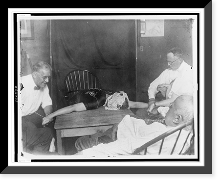 Woman medium lying on table, with ectoplasm on her head, surrounded by four other people, during seance, Vintage Print